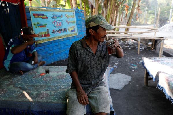 Сборщик мусора Салам пьет чай перед началом сортировки мусора в индонезийской деревне - Sputnik Беларусь