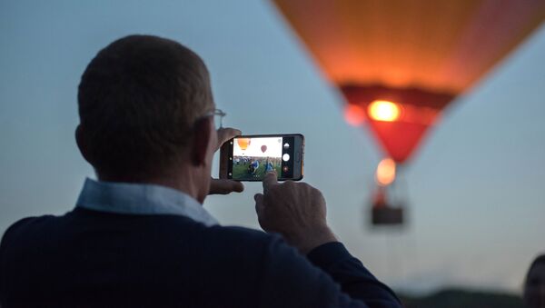 Мужчина фотографирует на телефон воздушный шар - Sputnik Беларусь