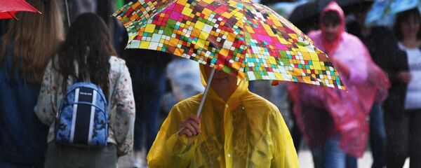 Женщина идет в дождевике и под зонтом во время дождя Женщина идет в дождевике и под зонтом во время дождя - Sputnik Беларусь