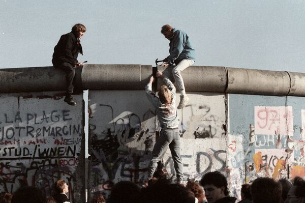 Жители ГДР ломают Берлинскую стену, 1989 год.Самую крепкую в мире стену свалили не политики, а простые люди.По воспоминаниям немцев, ощущение счастья и братства в тот день 9 ноября смыло все государственные барьеры и преграды. - Sputnik Беларусь