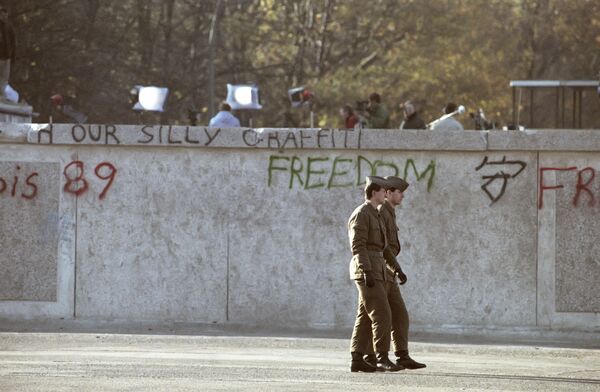 Пограннаряд у Берлинской стены с восточной стороны, октябрь 1989-го. Наиболее известны случаи побегов из ГДР следующими путями: 28 человек ушло по прокопанному ими самими тоннелю длиной 145 метров, совершались полеты на дельтаплане, на воздушном шаре из нейлоновых фрагментов, по веревке, перекинутой между окнами соседних домов, с помощью тарана стены бульдозером. Всего было совершено 5075 успешных побегов в Западный Берлин или ФРГ, в том числе 574 случая дезертирства. - Sputnik Беларусь