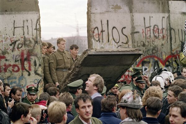 Западные берлинцы толпятся перед стеной в 1989 году, наблюдая за тем, как восточногерманские пограничники собираются открыть новый пункт пропуска между Восточным и Западным Берлином.Сотни тысяч восточных немцев устремились в тот же день к Стене. Пограничники, не получившие приказов, пытались сперва оттеснить толпу, использовали водометы, но затем, уступая массовому напору, вынуждены были открыть границу. - Sputnik Беларусь