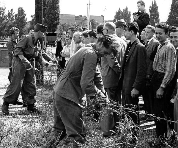 Восточно-германские солдаты устанавливают заграждения из колючей проволоки 13 августа 1961 года.За 28 лет своего существования стена в Берлине только росла по высоте и сложности. - Sputnik Беларусь