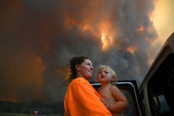 Шарни Морен и ее 18-месячная дочь Шарлотта смотрят, как густой дым поднимается от лесных пожаров недалеко от Кофс Харбора - Sputnik Беларусь