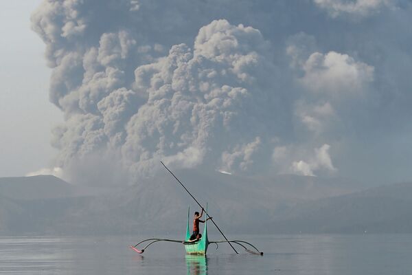 Молодой рыбак на каноэ у подножия вулкана Таал, извергающего пепел, к югу от Манилы - Sputnik Беларусь