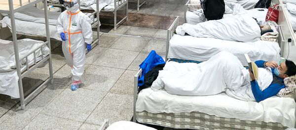Медицинские работники в защитных костюмах обслуживают пациентов в Международном выставочном центре Ухань - Sputnik Беларусь
