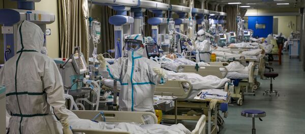 Медицинские работники в защитных костюмах обслуживают пациентов с коронавирусом в отделении интенсивной терапии специализированной больницы в Ухани - Sputnik Беларусь