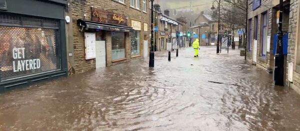 Человек идет по затопленной улице в Западном Йоркшире - Sputnik Беларусь