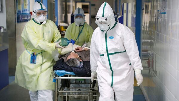 Медработники в защитных костюмах перевозят пациента - Sputnik Беларусь