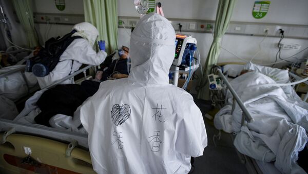 Медицинские работники в защитных костюмах работают с пациентами в больнице в Ухане - Sputnik Беларусь