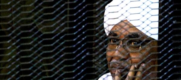 Бывший президент Судана Омар Хасан аль-Башир сидит в клетке в здании суда  - Sputnik Беларусь