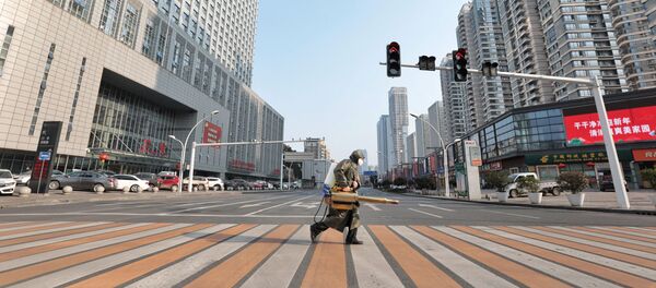 Рабочий с дезинфицирующим оборудованием пересекает дорогу перед больницей - Sputnik Беларусь