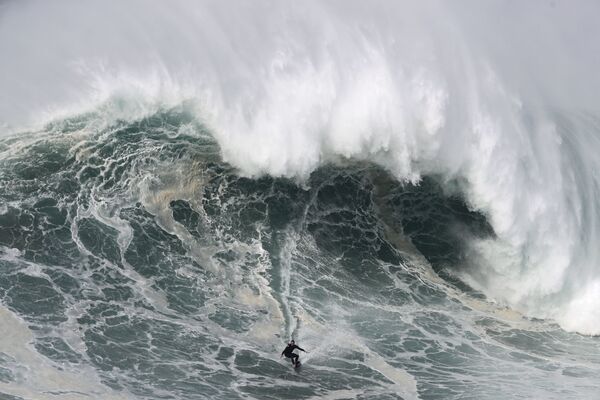 Серфер на гигантских волнах во время турнира Nazare Tow Surfing Challenge в Португалии  - Sputnik Беларусь