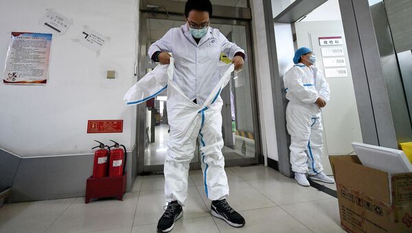 Человек надевает защитный костюм перед входом в лабораторию - Sputnik Беларусь