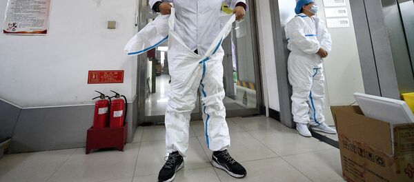 Человек надевает защитный костюм перед входом в лабораторию - Sputnik Беларусь