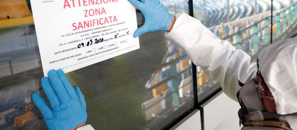 Уборщик в защитном костюме поправляет табличку с надписью Внимание: эта зона была продезинфицирована Уборщик в защитном костюме поправляет табличку с надписью Внимание: эта зона была продезинфицирована - Sputnik Беларусь