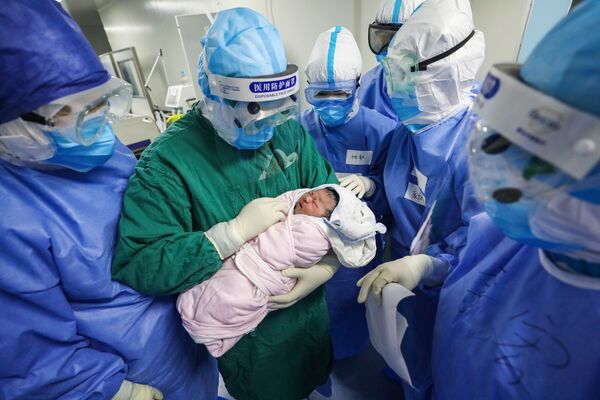 Врач держит новорожденного ребенка в отделении гинекологии и акушерства для будущих мам, инфицированных COVID-19 - Sputnik Беларусь