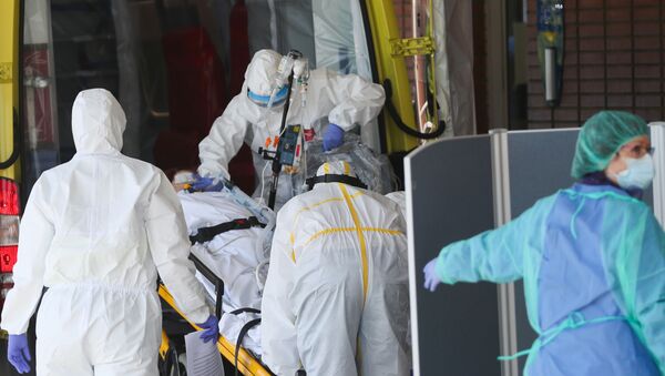 Медицинский персонал доставляет пациента с коронавирусом в больницу во время пандемии COVID-19 в Испании - Sputnik Беларусь