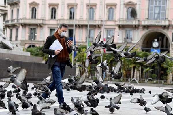 Мужчина в маске идет среди голубей в центре Милана, Италия - Sputnik Беларусь