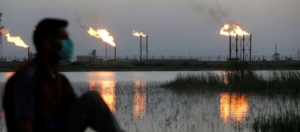 Мужчина в маске смотрит на пламя из факельных труб на нефтяном месторождении Нахр Бин Умар к северу от Басры, Ирак Мужчина в маске смотрит на пламя из факельных труб на нефтяном месторождении Нахр Бин Умар к северу от Басры, Ирак - Sputnik Беларусь
