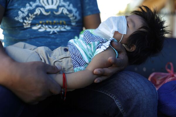 Мужчина со спящим ребенком в медицинской маске на руках в Сантьяго, Чили - Sputnik Беларусь