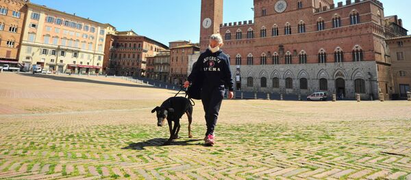 Женщина в медицинской маске гуляет с собакой по заросшей травой площади Пьяцца-дель-Кампо в Сиене, Италия - Sputnik Беларусь