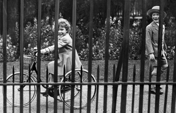 4-летняя Елизавета катается на велосипеде. Справа ее двоюродный брат Джеральд Ласселл. Через месяц у принцессы появилась младшая сестра Маргарет. - Sputnik Беларусь
