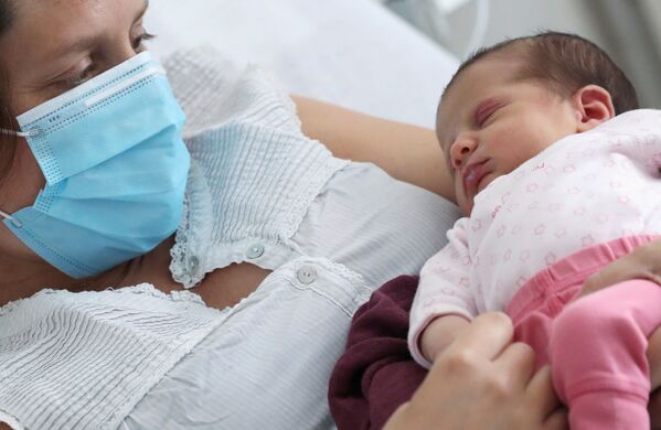 Зараженная коронавирусом женщина в защитной маске с новорожденной дочерью в больнице Брюсселя, Бельгия - Sputnik Беларусь