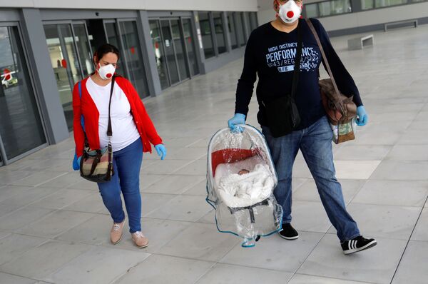 Супруги в защитных масках и с новорожденным сыном покидают больницу в городе Ронда, Испания - Sputnik Беларусь