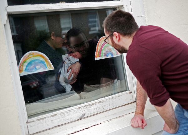Мужчина смотрит через окно на свою новорожденную племянницу в период пандемии коронавируса в Великобритании - Sputnik Беларусь