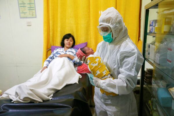  Медсестра в защитном костюме держит новорожденного в родильном отделении в Депоке, недалеко от Джакарты, Индонезия - Sputnik Беларусь