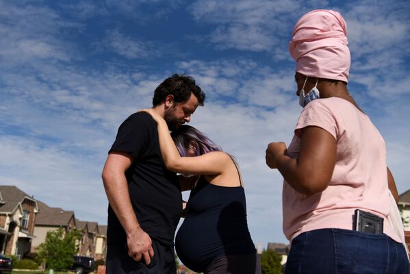 Беременная женщина испытывает схватки во время прогулки со своим партнером возле дома акушерки во время эпидемии коронавируса Форт-Уэрте, штат Техас, США - Sputnik Беларусь