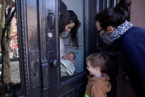 Мать показывает своего новорожденного ребенка сестре и племяннику через стекло в Бруклинском районе Нью-Йорка, США - Sputnik Беларусь