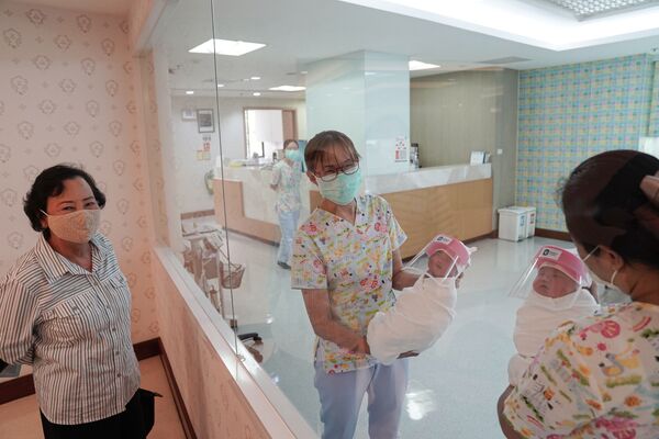 Медсестры в защитных лицевых масках держат новорожденных в защитных лицевых щитках в целях профилактики коронавируса в больнице в Бангкоке, Таиланд - Sputnik Беларусь