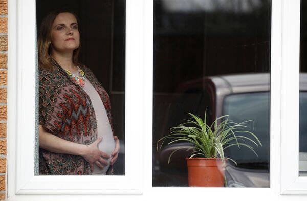 Беременная женщина у окна своей гостиной в Манчестере, Великобритания - Sputnik Беларусь