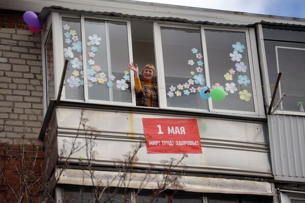 Женщина на балконе жилого дома в Свердловской области, украшенном первомайскими лозунгами - Sputnik Беларусь