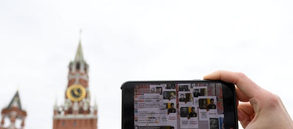 Молодой человек смотрит трансляцию акции Бессмертный полк на Васильевском спуске в Москве - Sputnik Беларусь