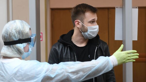 Мужчина после измерения температуры при входе в лечебное учреждение - Sputnik Беларусь