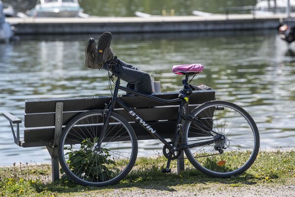 Мужчина поставил свой велосипед и отдыхает на скамейке - Sputnik Беларусь