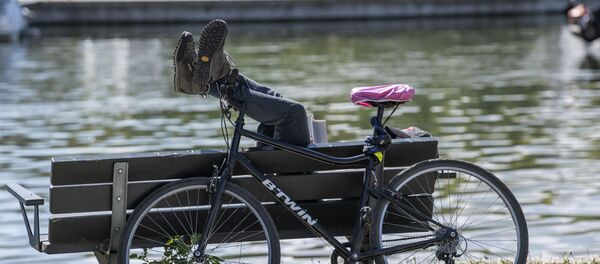 Мужчина поставил свой велосипед и отдыхает на скамейке - Sputnik Беларусь