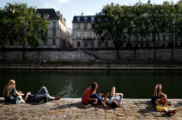 Люди наслаждаются солнечной погодой, сидя на берегу Сены в Париже - Sputnik Беларусь