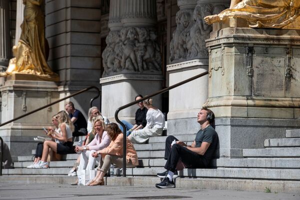 Люди наслаждаются солнечной погодой, сидя на лестнице Королевского драматического театра в Стокгольме - Sputnik Беларусь