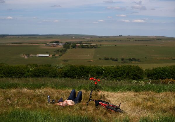 Мужчина отдыхает в поле после снятия карантина в Великобритании - Sputnik Беларусь