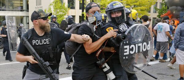 Полицейский толкает фотографа во время протестов в США Полицейский толкает фотографа во время протестов в США - Sputnik Беларусь