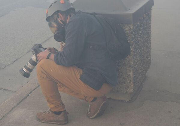 Фотокорреспондент Reuters Карлос Барриа прячется за мусорным баком от государственного патруля штата Миннесота - Sputnik Беларусь
