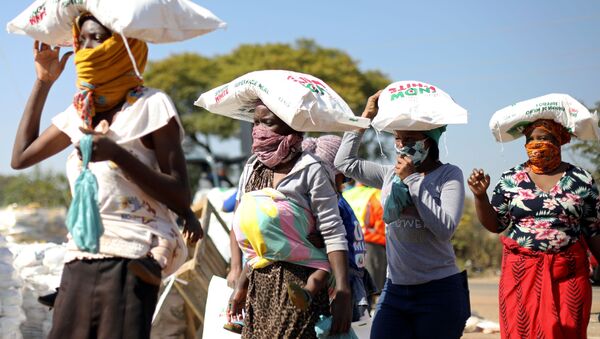 Женщины несут мешки с мукой на голове, выданной как продовольственная помощь на фоне распространения коронавируса в ЮАР - Sputnik Беларусь