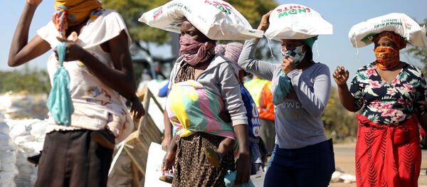 Женщины несут мешки с мукой на голове, выданной как продовольственная помощь на фоне распространения коронавируса в ЮАР - Sputnik Беларусь