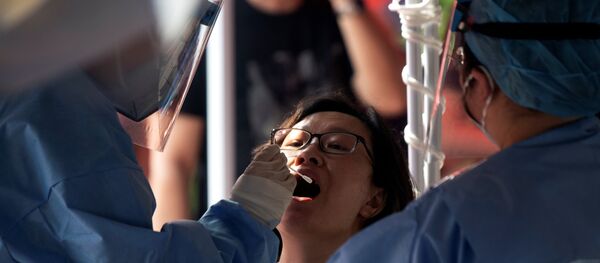 Медицинский работник в защитном костюме берет мазок у женщины на открытой площадке во время массового тестирования на коронавирус COVID-19 в Пекине 23 июня 2020 года. Медицинский работник в защитном костюме берет мазок у женщины на открытой площадке во время массового тестирования на коронавирус COVID-19 в Пекине 23 июня 2020 года. - Sputnik Беларусь