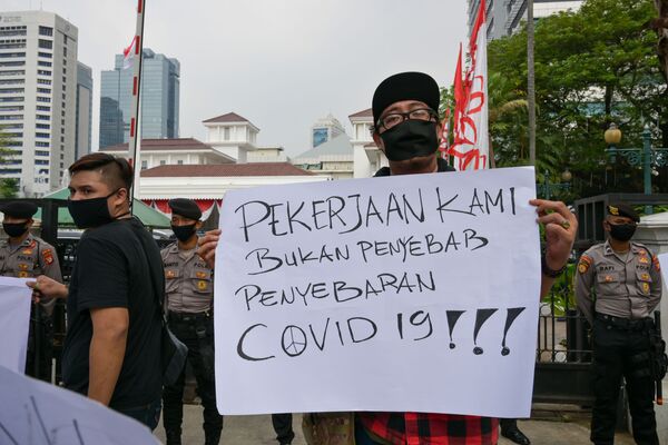 Индонезийский музыкант держит плакат с надписью: Наша профессия не является причиной распространения COVID-19! - Sputnik Беларусь